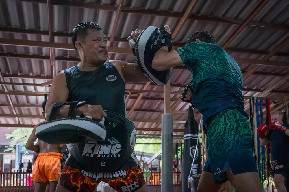 Kru Rit holding pads during a Muay Thai training round at Kiatphontip