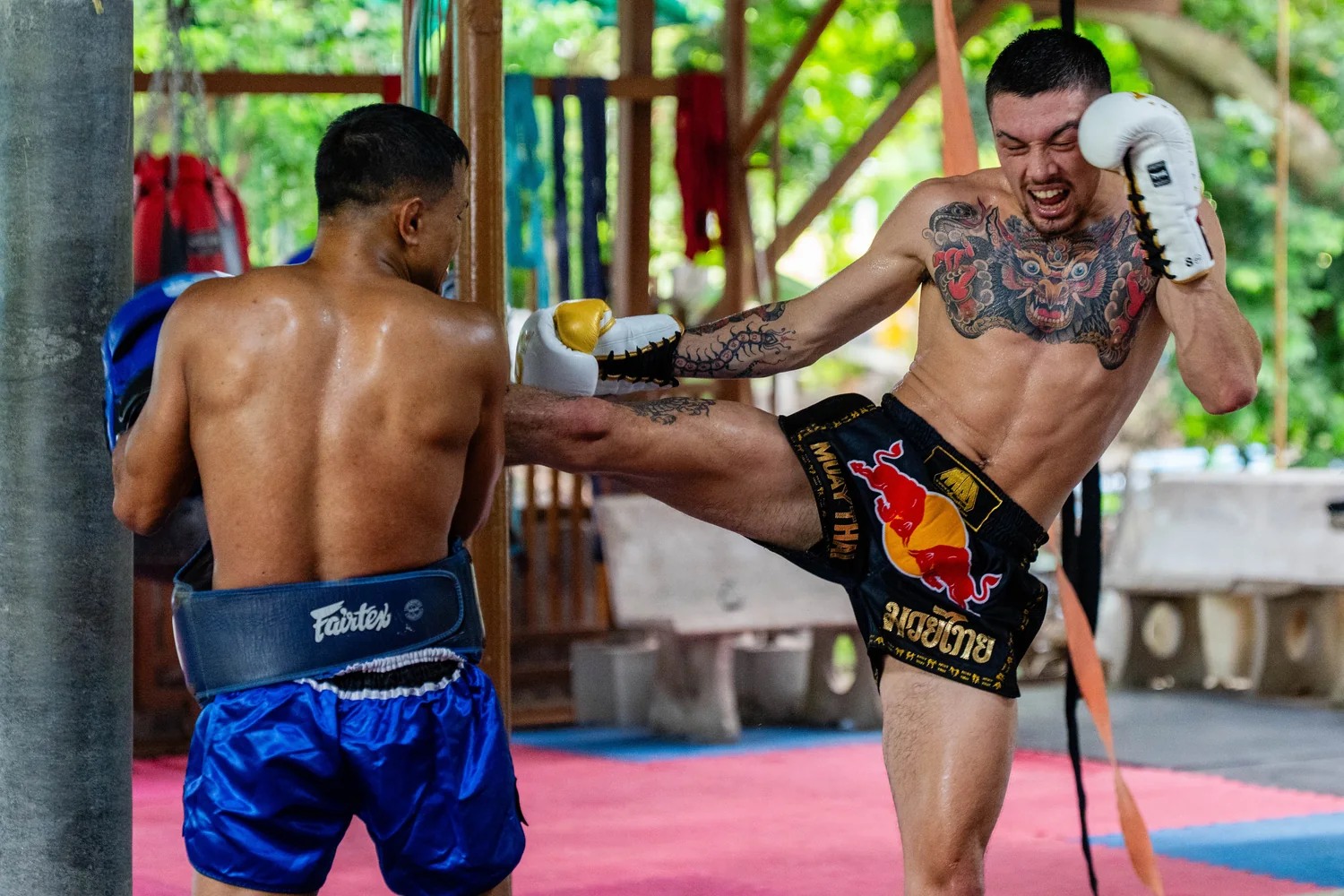Trainer holding pads for a kicking student at Kiatphontip