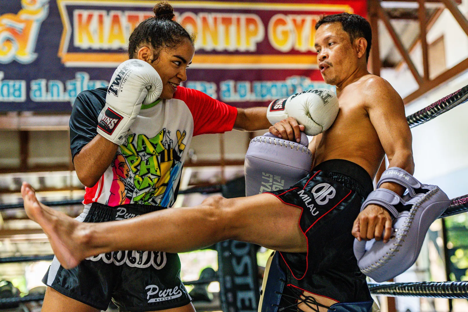 Knee strike on the pads under the Kiatphontip Gym banner