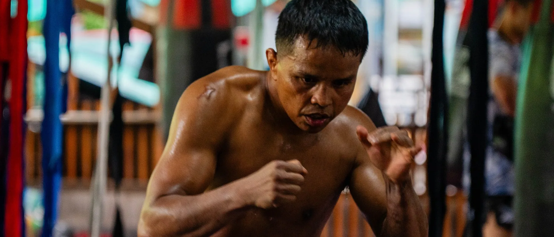 Thai kru shadowboxing between the bags at Kiatphontip Muay Thai camp, Bangkok