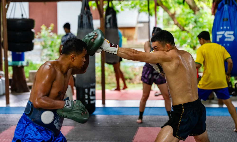 Fighter drilling kicks on the pads at Kiatphontip camp