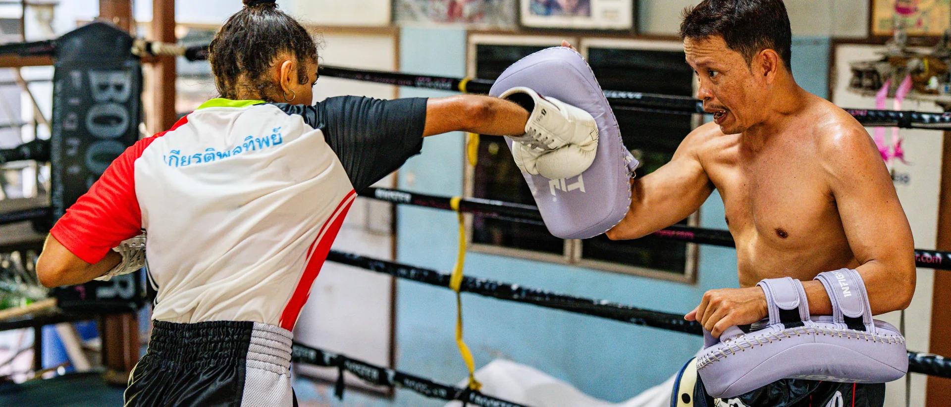 Woman training Muay Thai kicks on the pads at Kiatphontip, Bangkok